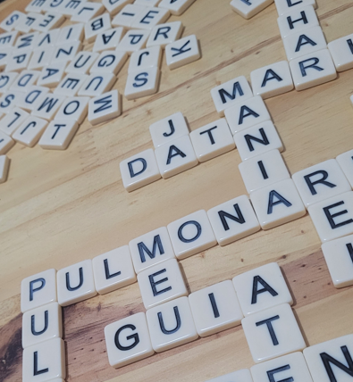 Peças com letras formando palavras cruzadas sobre uma mesa durante uma partida.